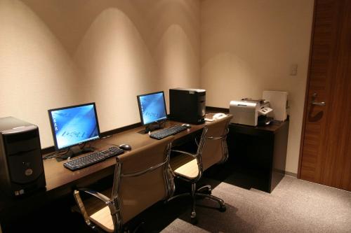 a desk with three computers on top of it at ANA Crowne Plaza Kumamoto New Sky by IHG in Kumamoto