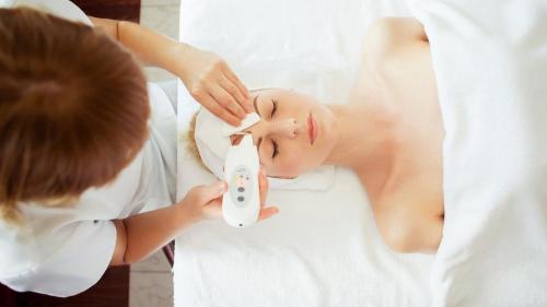 a woman brushing her face with a wii remote at Stare Łazienki in Nałęczów