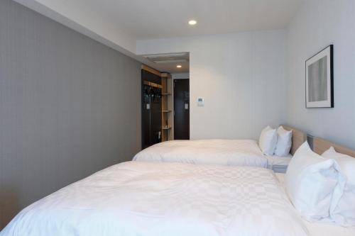 two beds in a room with white sheets at Tmark City Hotel Tokyo Omori in Tokyo
