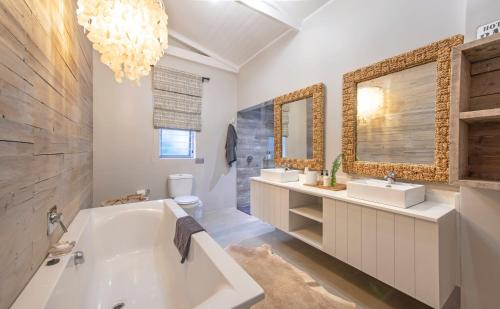 a bathroom with a tub and two sinks and a mirror at Driftwood by The Oyster Collection in Kenton on Sea