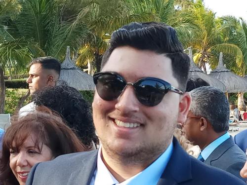 a man wearing sunglasses and a suit and some people at The Monalysa Suites & Residence in Grand Baie