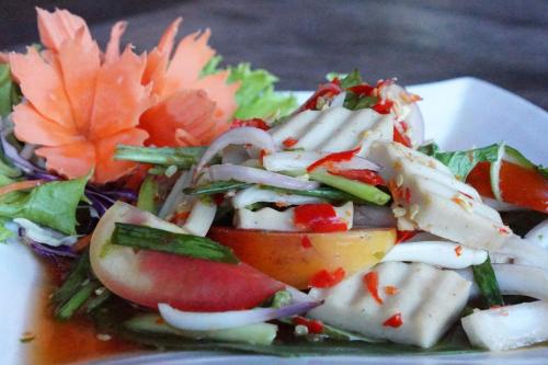 a salad on a white plate with tomatoes and vegetables at Tara Lake in Bangkok