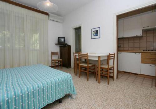 1 dormitorio con cama, mesa y cocina en Villa al Mare Camping-Village - 4 Stelle, en Cavallino-Treporti