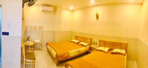 1 dormitorio con 2 camas, mesa y silla en Quang Vinh - Đảo Lý Sơn en Ly Son