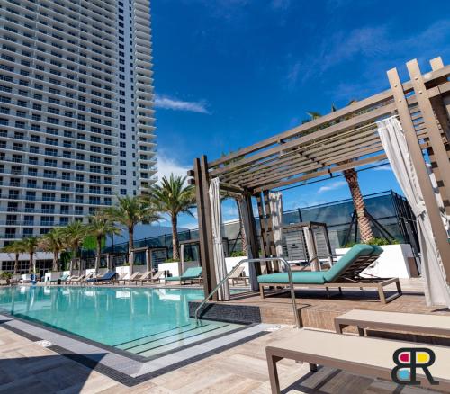 a swimming pool with chairs and a large building at HYDE Beach House Apartments in Hollywood