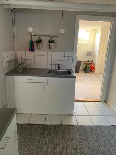 a kitchen with white cabinets and a sink at Surf Apartment Stormgade in Hvide Sande