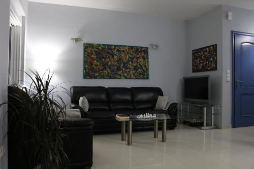 a living room with a black leather couch and a tv at Laconian Collection "Lykourgou 10" in Sparta