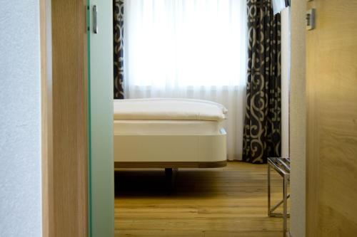 Bett in einem Zimmer mit Fenster in der Unterkunft Hôtel-Restaurant du Cerf in Sonceboz