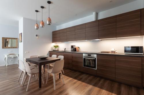 una cocina con armarios de madera, mesa y sillas en Brand new flat heart of Vilnius en Vilna