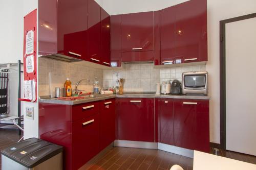 - une cuisine équipée de placards rouges et d'un four micro-ondes dans l'établissement Panoramic Plaza Apartment -Loreto 1, à Milan