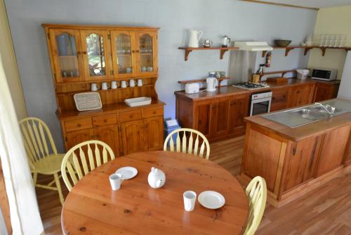 une cuisine avec une table en bois et une table et des chaises dans l'établissement Wallum cottages, à Crescent Head