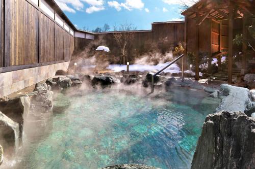 a hot spring in a garden with snow on the ground at KAMENOI HOTEL Kusatsu Resort in Kusatsu