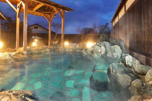 a hot tub with rocks in a backyard at night at Kusatsu-onsen Hotel Resort in Kusatsu