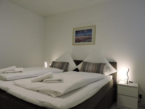 um quarto com 2 camas e lençóis brancos em Ferienwohnungen Sophie em Saarbrücken