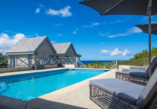 a swimming pool with two lounge chairs and an umbrella at West Rock Villas in Saint James