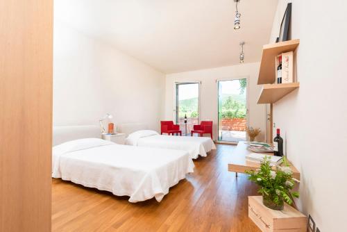 two beds in a white room with a table and chairs at La Foresteria di Rocca di Frassinello in Gavorrano