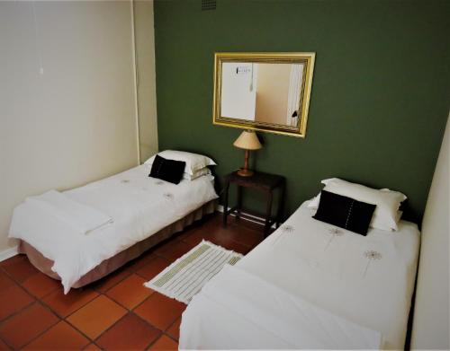 two beds in a room with green walls and a mirror at Fountain Baths Guest Cottages in Barberton