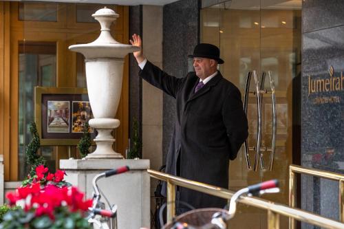 a man in a suit and top hat standing outside a building at The Lowndes London - A Jumeirah Partner Hotel in London