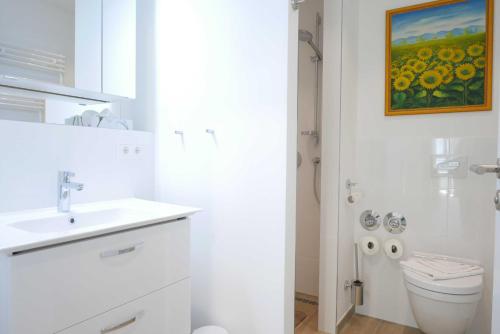 a white bathroom with a sink and a toilet at Baabe Villen Ensemble FeWo 02 Kais in Baabe