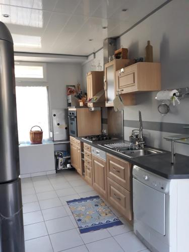 une cuisine avec un évier et une cuisinière four supérieur dans l'établissement L'Ancienne Forgerie de Sainte mère Eglise, à Sainte-Mère-Église