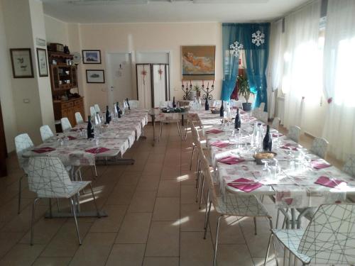 une salle de conférence avec de longues tables et chaises dans l'établissement Ostello Angolo Verde, à Angolo Terme