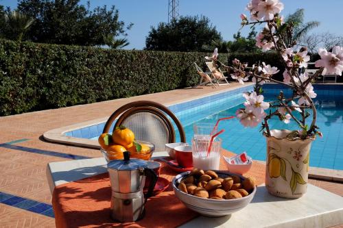 una mesa con un bol de fruta junto a una piscina en B&B Il Mandorleto Avola, en Avola