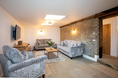 a living room with couches and a brick wall at The Yard @ Pringle Farm in Great Stukeley