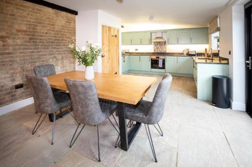 uma cozinha com uma mesa de madeira e cadeiras em The Yard @ Pringle Farm em Great Stukeley