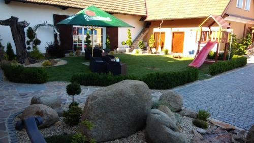 a garden with a house with a green umbrella at Restaurace čp.2 in Slapy