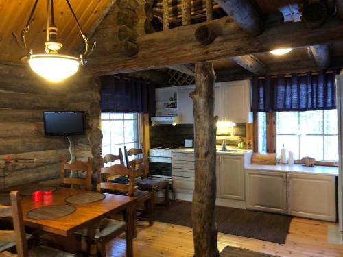 cocina y comedor con mesa en una cabaña en Villa Kelotupa, en Hossa