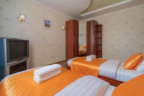 a hotel room with two beds and a television at Five Stars on the Waterfront in Nizhnevartovsk