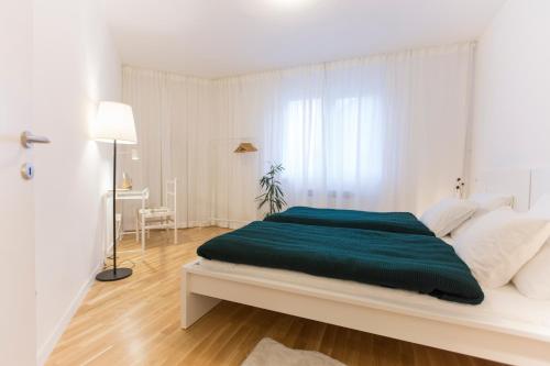 ein weißes Schlafzimmer mit einem großen Bett und einer grünen Decke in der Unterkunft apt.vrbik in Zagreb