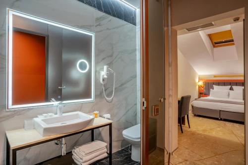 een badkamer met een wastafel, een toilet en een bed bij Barin Residence Myasnitskaya in Moskou