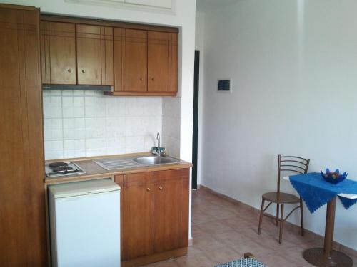 a kitchen with wooden cabinets and a sink and a table at Dionisis Studios in Város