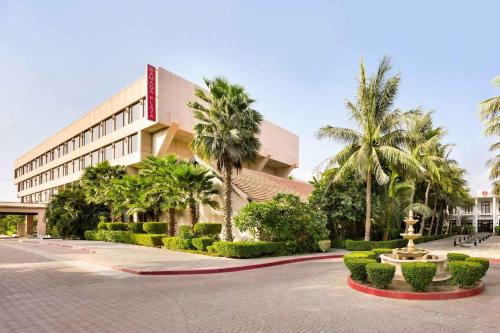 a building with palm trees and a fountain in front of it at Ramada Plaza by Wyndham Karachi Airport Hotel in Karachi
