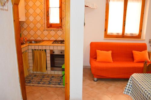 リド・マリーニにあるCasa Vacanza CALALUNAのリビングルーム(オレンジ色のソファ付)、キッチンが備わります。