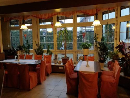 restauracja z dwoma stołami, krzesłami i oknami w obiekcie Pension Schulze w mieście Oranienbaum-Wörlitz