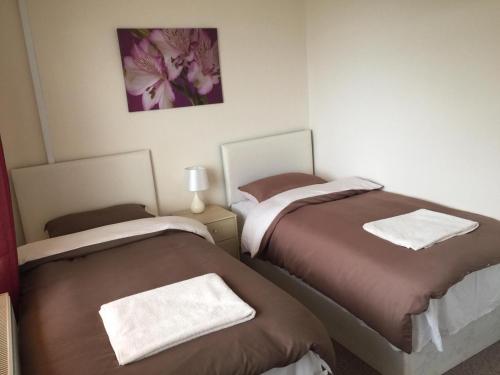 a bedroom with two beds with towels on them at Laughing Buddha Guesthouse in Uddingston