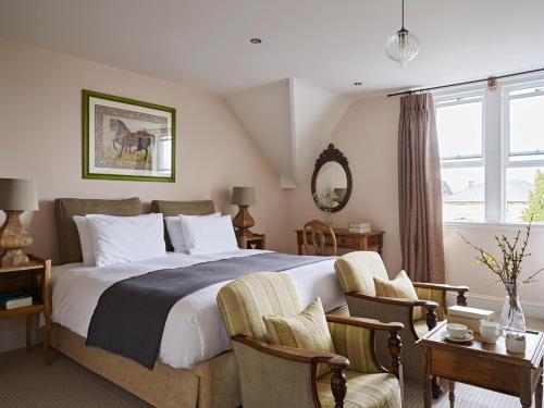 a bedroom with a large bed with two chairs at Cotswold Grange in Cheltenham