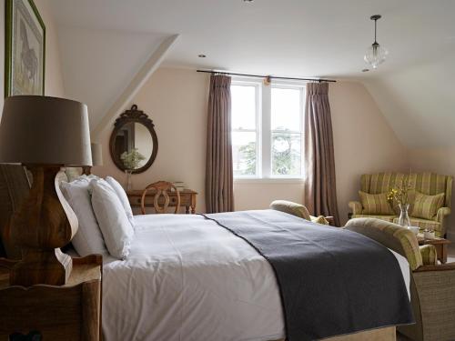 a bedroom with a bed and a chair and a window at Cotswold Grange in Cheltenham