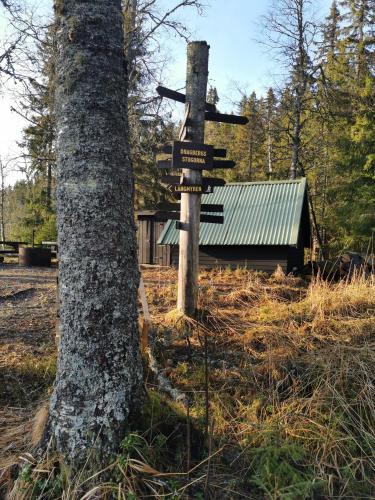 a wooden sign next to a tree next to a building at Hyttingsfabodstugor in Borlänge
