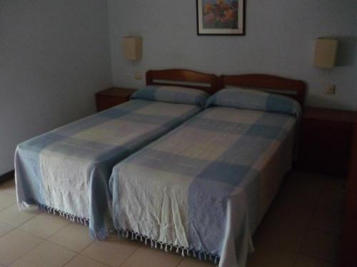 um quarto com 2 camas com lençóis azuis e brancos em Hostal El Centro em Huesca
