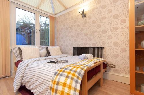 une chambre avec un lit avec une couverture à carreaux dans l'établissement Oasis 77, à Londres