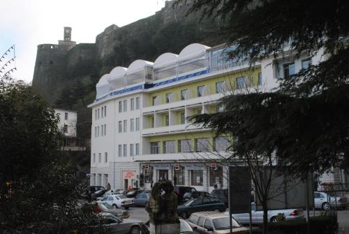 un grand bâtiment blanc avec une montagne en arrière-plan dans l'établissement Hotel Cajupi, à Gjirokastër