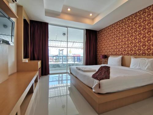 um quarto com uma cama e uma grande janela em Le Desir Resortel em Chalong