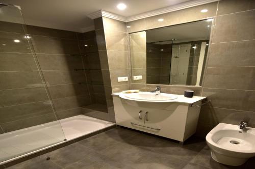 a bathroom with a sink and a toilet and a mirror at New apartamento Bajo en Isla de la Toja. in Isla de la Toja