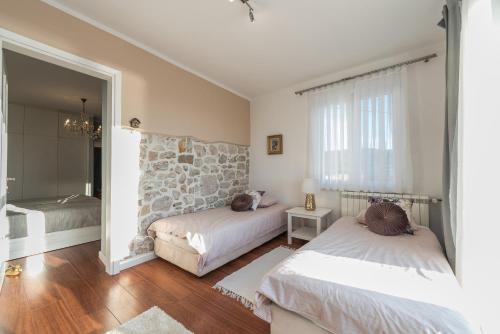 a bedroom with two beds and a stone wall at Villa Rosa in Pašman