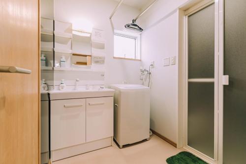 a white bathroom with a sink and a shower at Stay In Biei in Biei