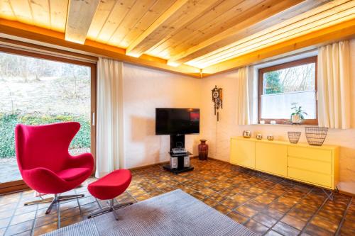 un salon avec une chaise rouge et une télévision dans l'établissement Ferienwohnungen Alpentraum - Ferienhaus Schmid, à Oberstdorf