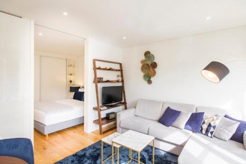 een witte woonkamer met een bank en een bed bij São Bento Hill View in Porto